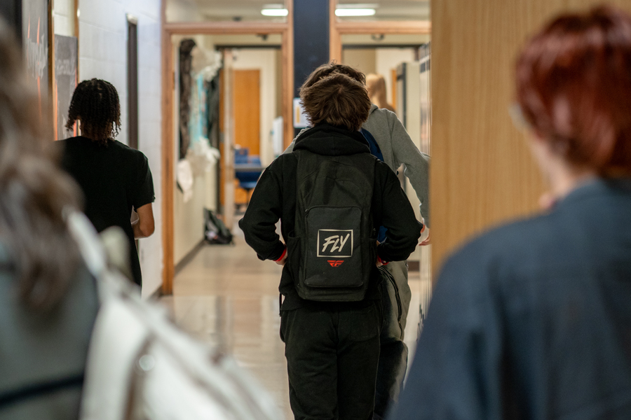 A photo of students walking down the halls, away from the camera, inside Central High School