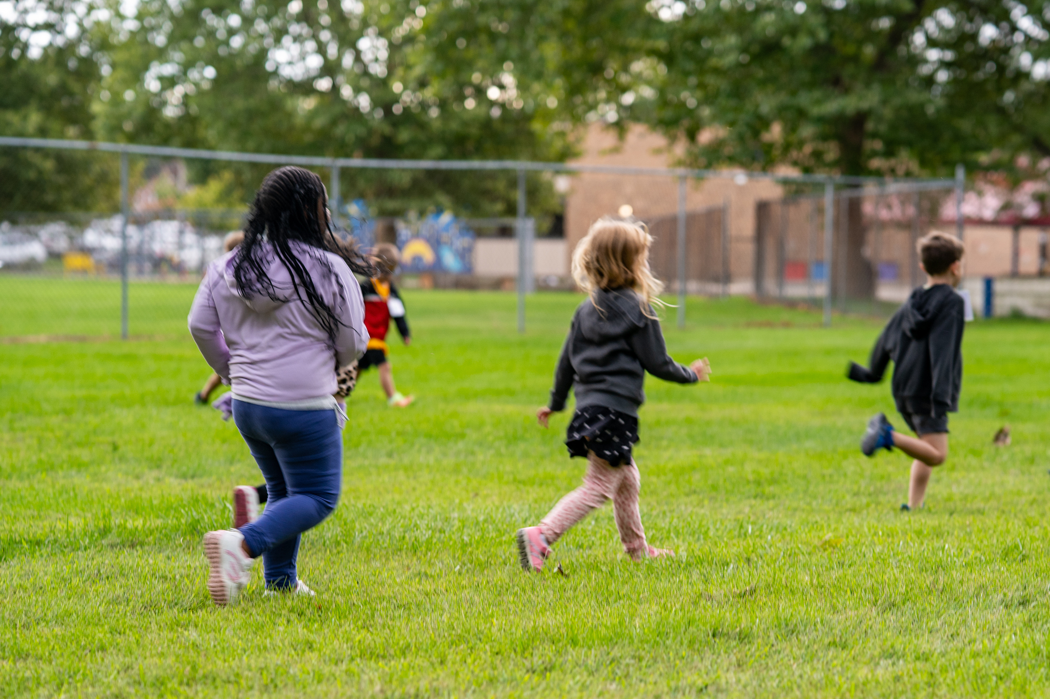 Children running in a field near a playground