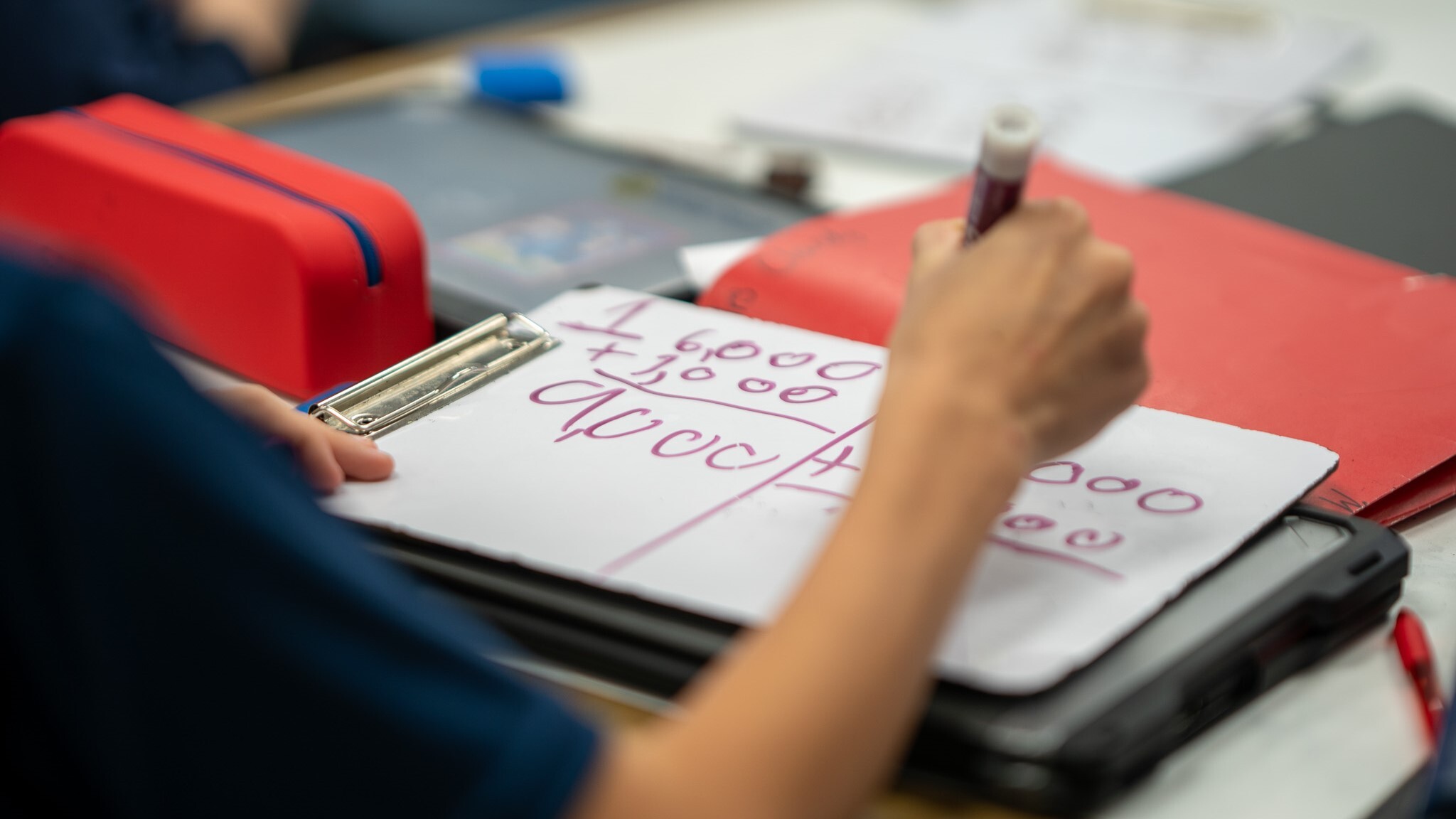 A student writing on a whiteboard with a marker