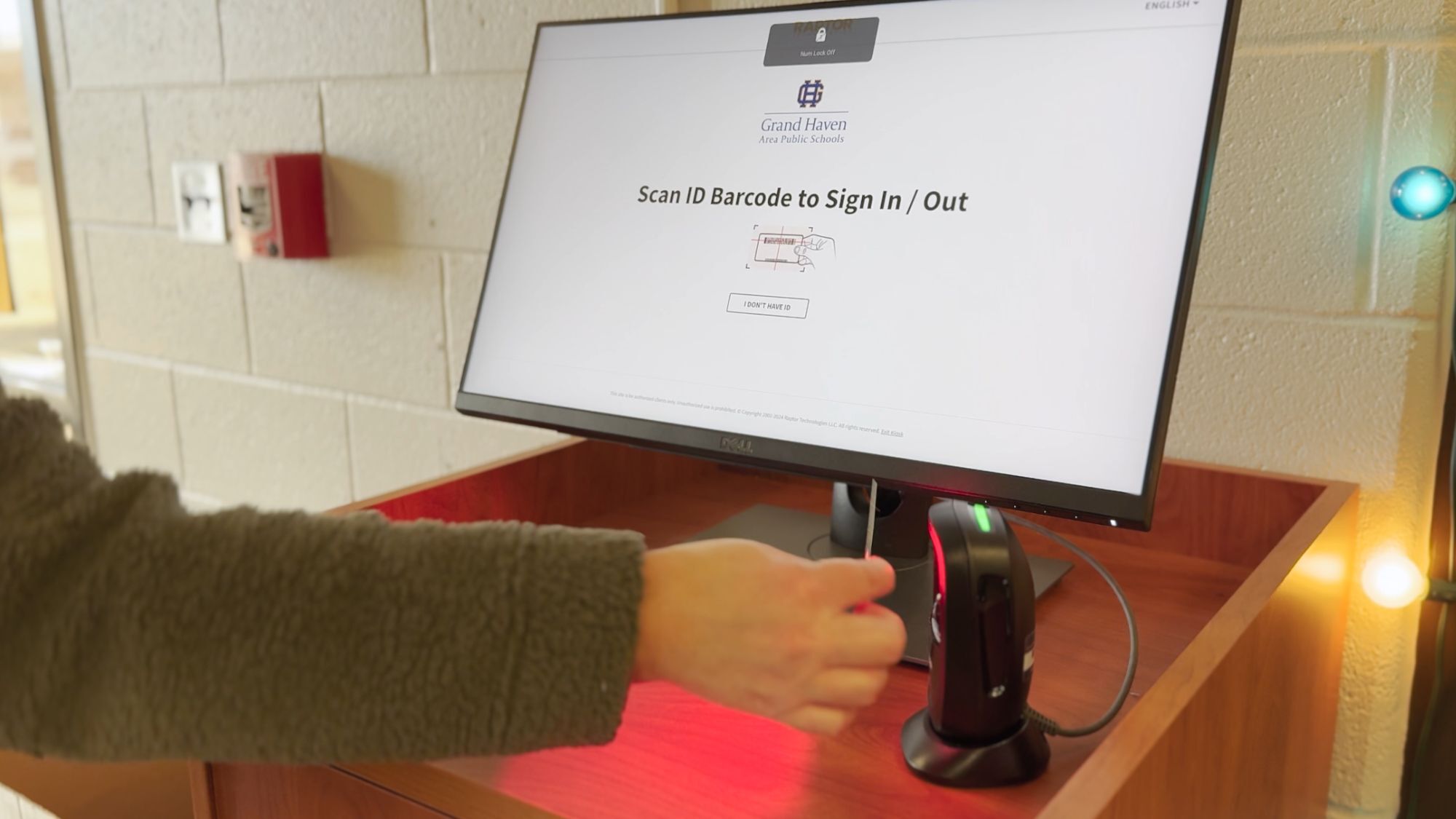 The arm of a GHAPS school visitor scanning an ID to sign into the system