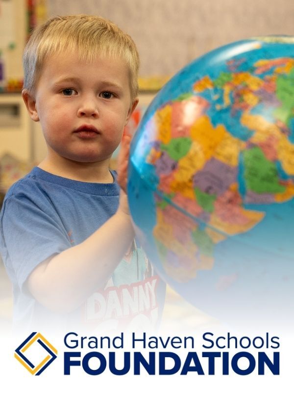 A preschool student playing with a globe and the Grand Haven Schools Foundation Logo