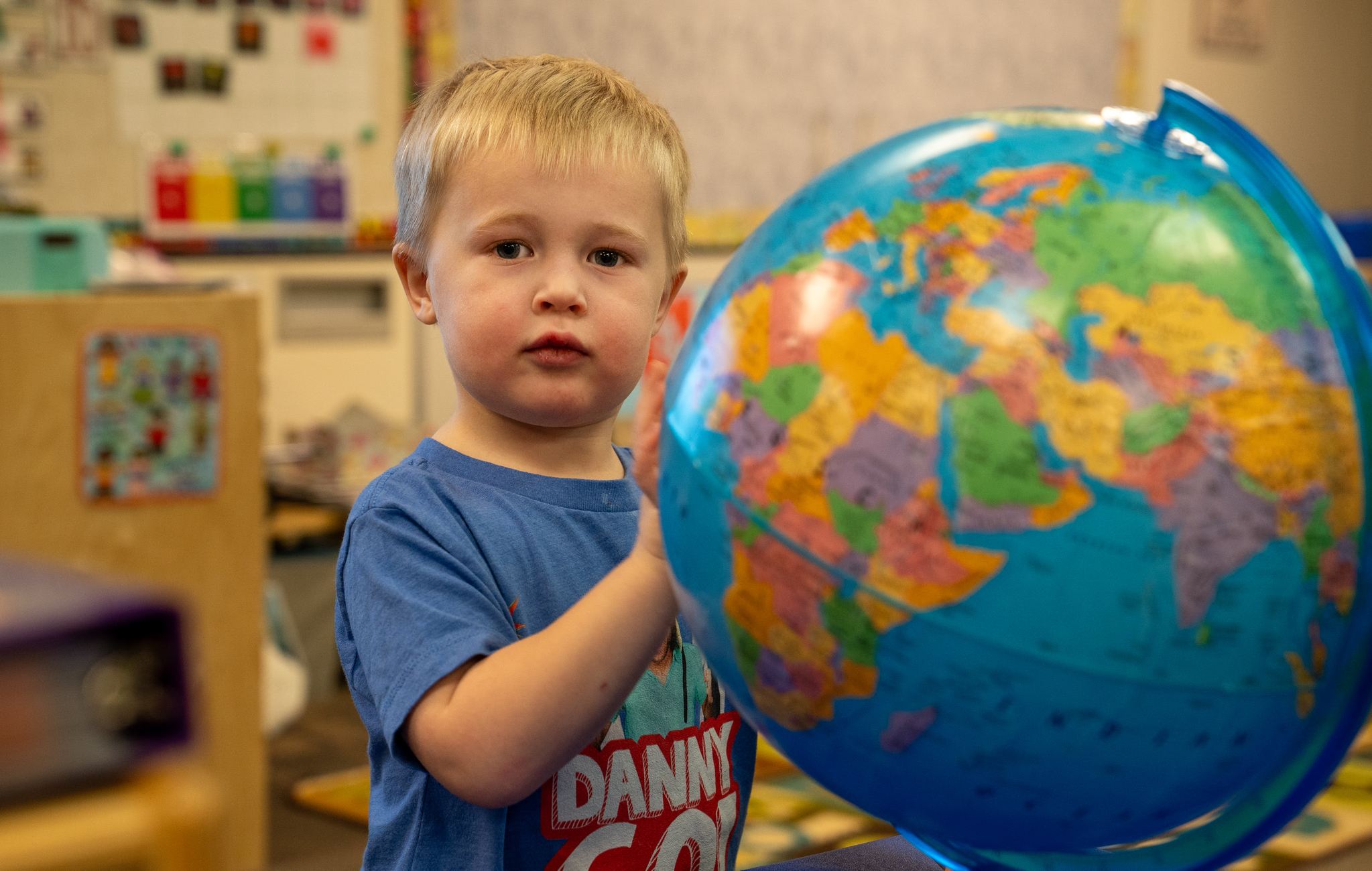 A young preschool student playing with a globe.