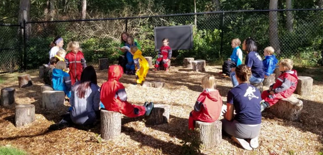 Students sitting on log seats in an outdoor learning environment