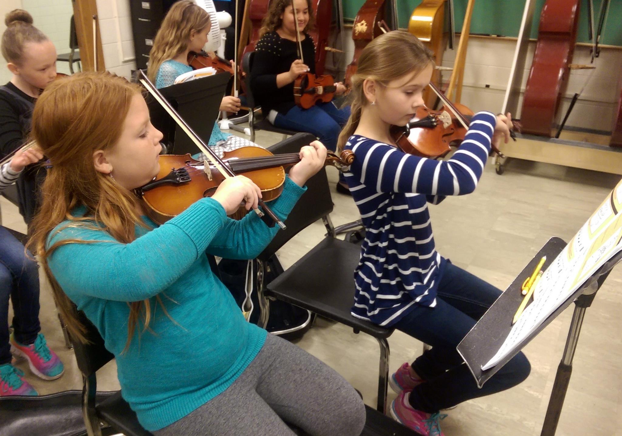 two girls playing violin during orchestra practice